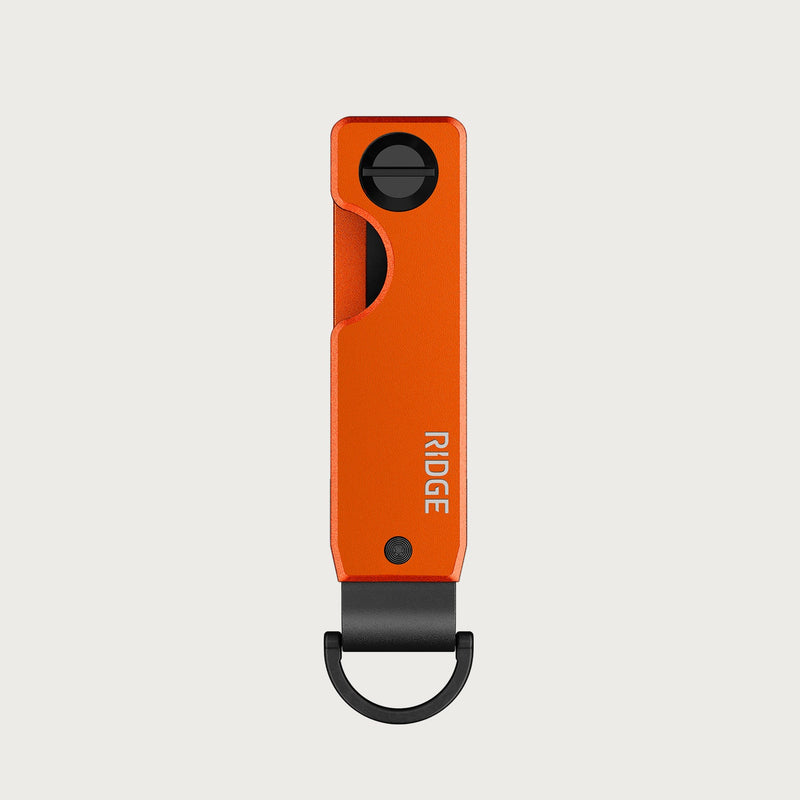 Ridge KeyCase in Basecamp Orange, front view showing the Ridge logo, screw closure, and black carabiner loop.